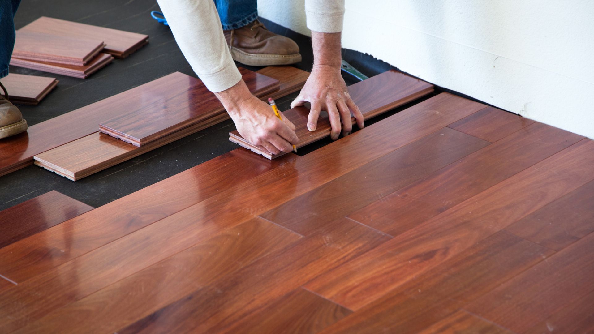 Hands measuring and installing wooden flooring planks during home renovation