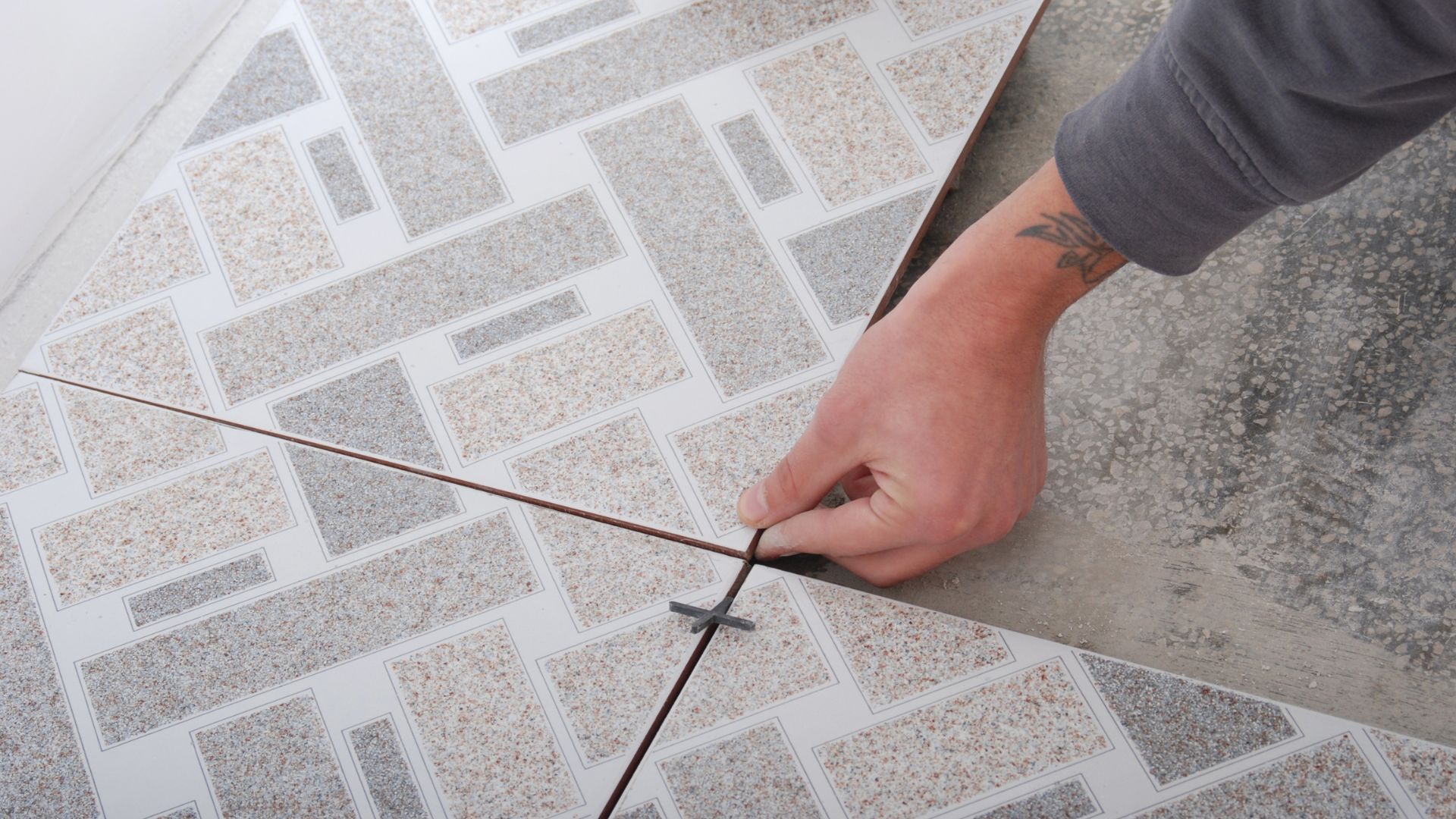 Hand placing tile spacer between textured stone tiles during installation