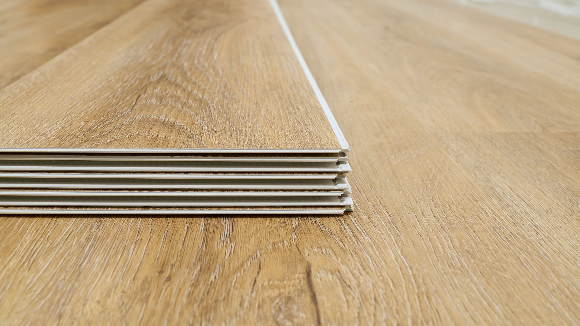 Stacked wooden planks with gray backing on a wooden surface