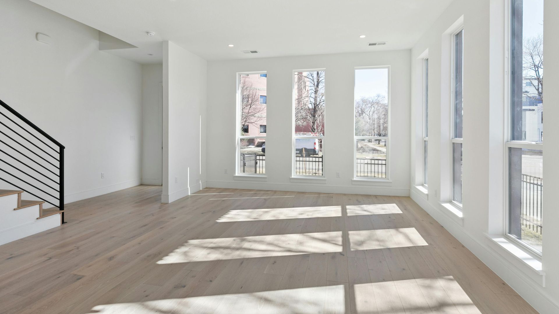 Bright empty room with large windows, wood floors, and natural light