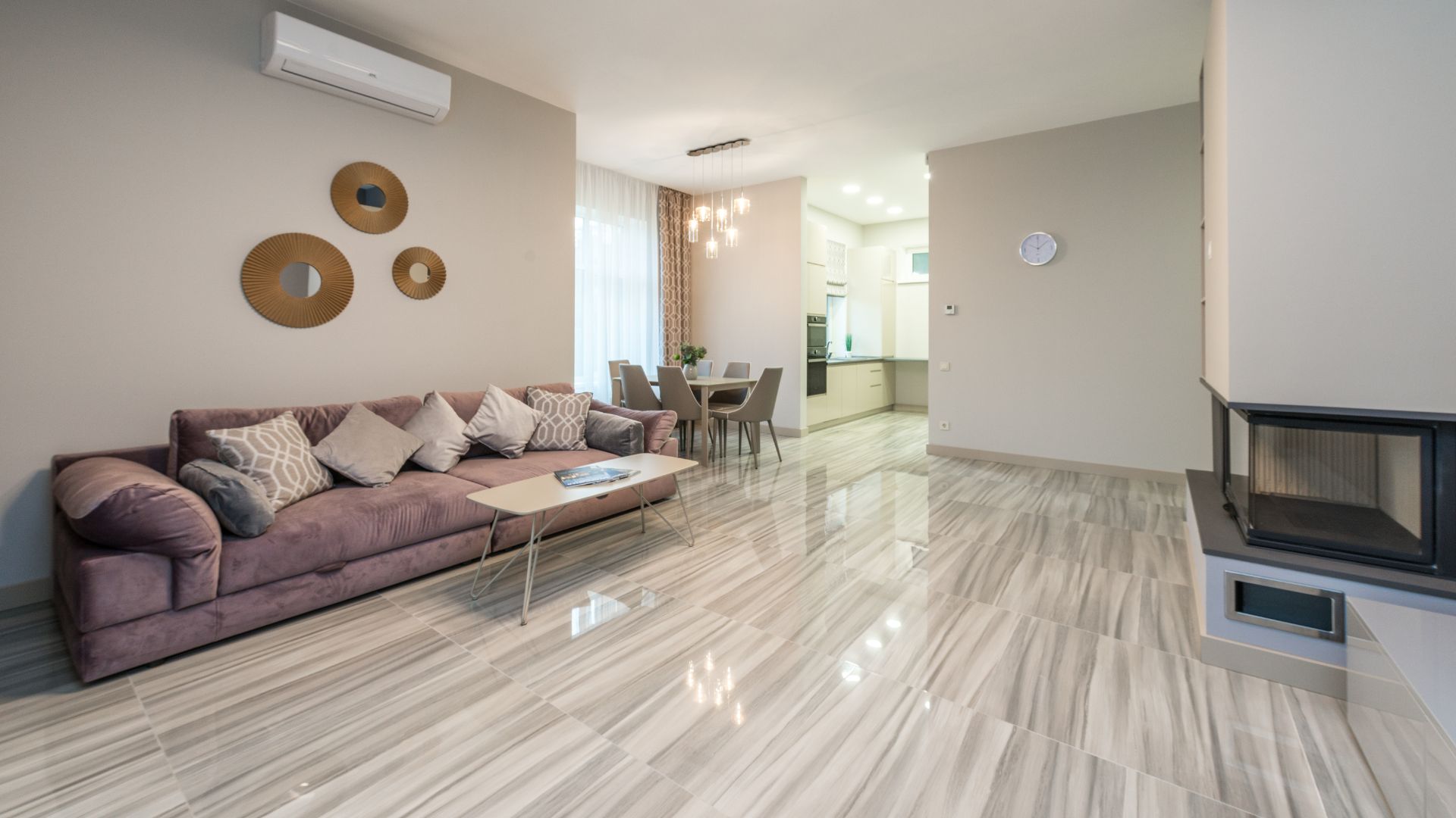 Modern open-plan living room with pink sofa, dining area, and glossy floor