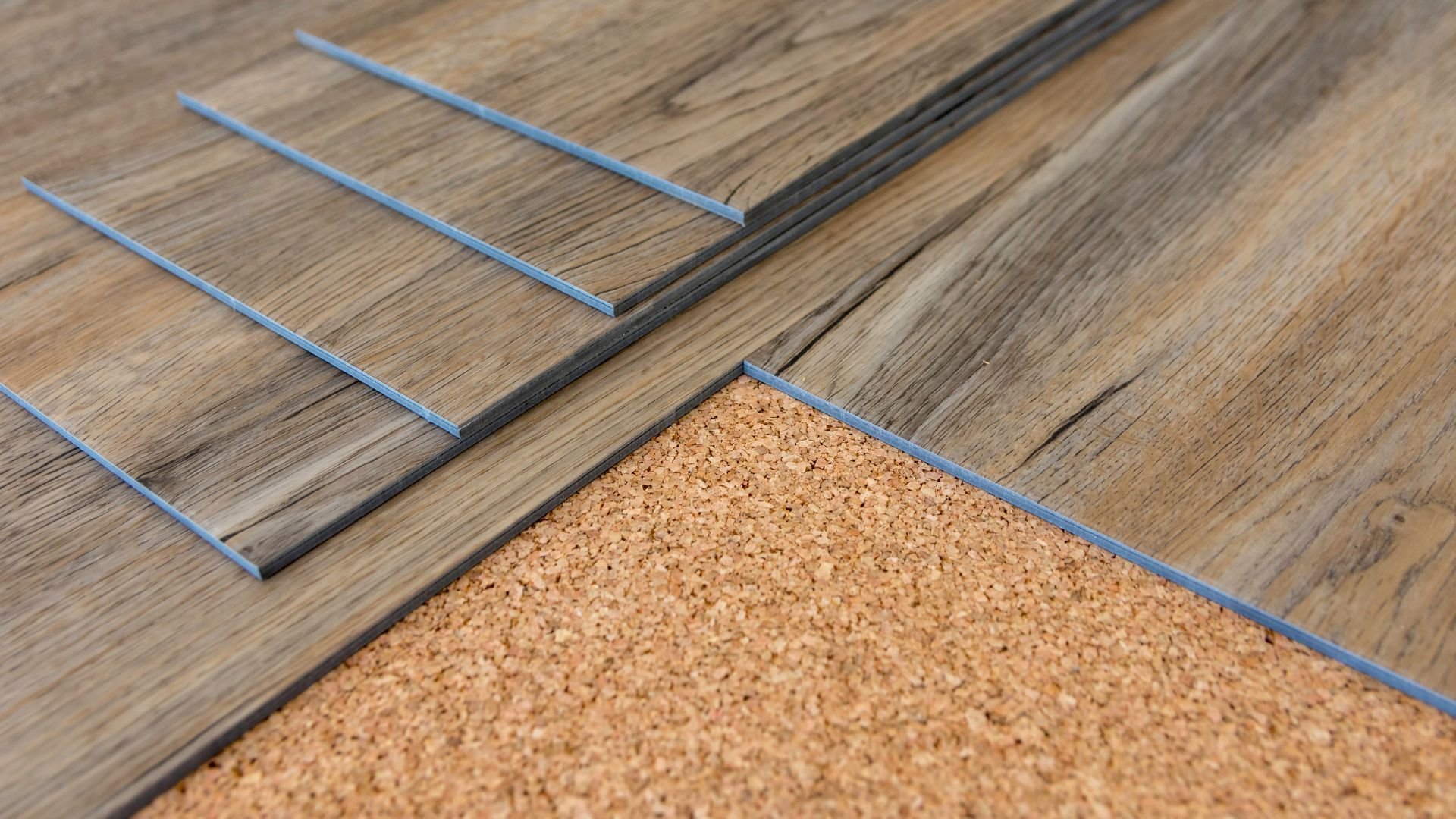 Flooring installation with wood panels and blue trim on cork substrate